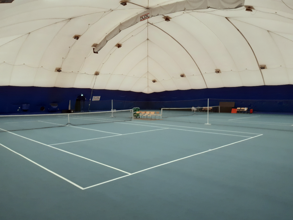 Kuvassa kaksi tenniskenttää Savitaipaleen tennishallissa.